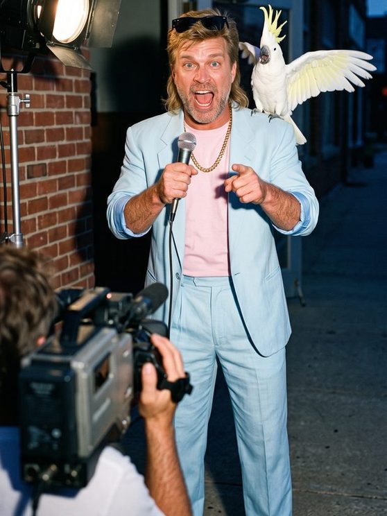 Manny Mayhem in a pastel baby-blue suit shooting a TV ad outside the gym